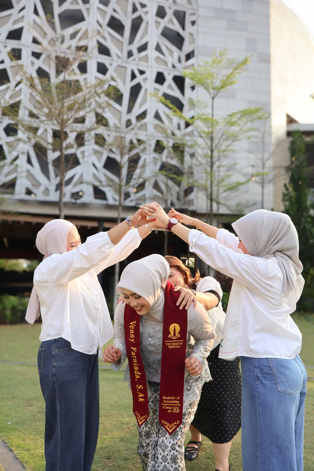 Momen wisuda outdoor yang hangat, dikelilingi keluarga dan sahabat di taman